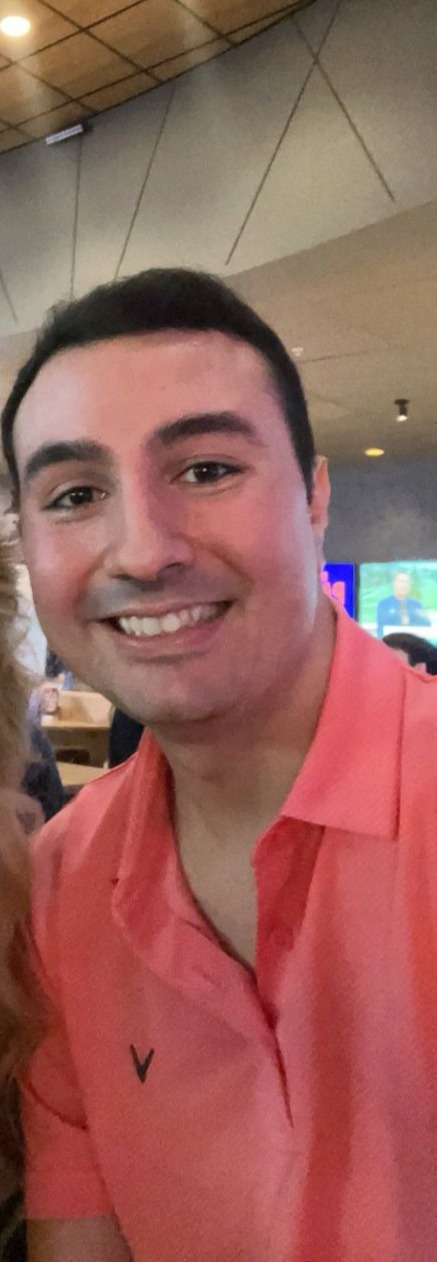 Sam grinning in a coral polo